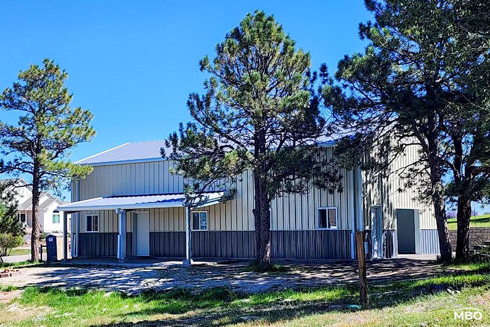 cold-formed-garage-co a cold formed building with wainscot and a lean to overhang over the steel walk door entrance